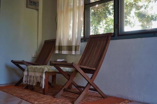 two wooden chairs with a table and a window at ComeOn Stay&Sleep in Chiang Rai