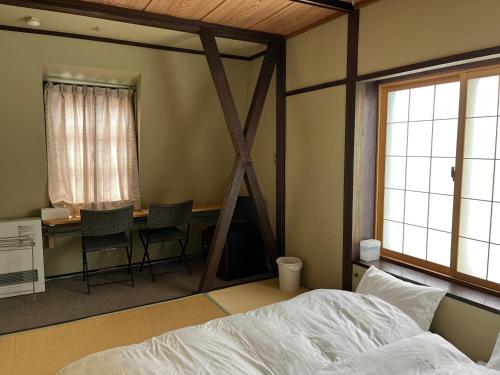 a bedroom with a bed and a desk and windows at Aigakusou in Nozawa Onsen
