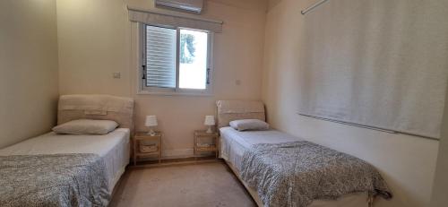 two twin beds in a room with a window at Lydia's Sea View - 2 bed House in Episkopi Lemesou