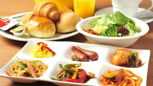 ein Tisch mit Tellern voller Essen auf einem Tisch in der Unterkunft Hotel Paco Obihiro Ekimae in Obihiro