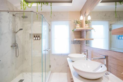 a bathroom with two sinks and a glass shower at Kira Japandi Escape with Sauna & Rooftop cinema in Hua Hin