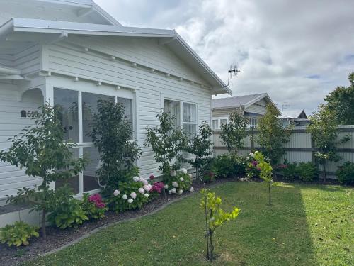 a white house with a garden in front of it at Luxury Magnolia Bungalow in Hastings