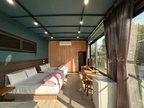 a room with three beds and a table and a window at Mei Nong Villa in Meinong