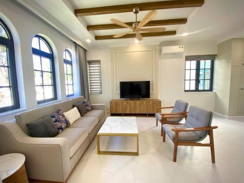 ein Wohnzimmer mit Couch und Flachbildfernseher in der Unterkunft 3BR Villa Novaworld Phan Thiet in Bình Tú