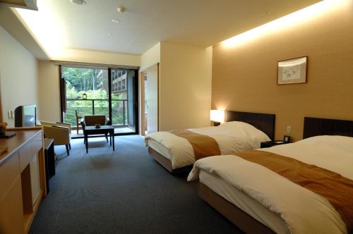 a hotel room with two beds and a desk at Setsugetsuka in Hakone