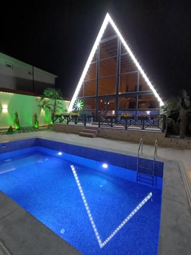 a swimming pool with lights in front of a building at A Frame Houses in Sheki