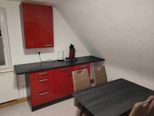 a kitchen with red cabinets and a table with chairs at Charlotte II in Neustadt bei Coburg