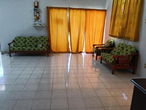 a living room with two chairs and orange curtains at Homestay Jannati Bandar Baru Putra Ipoh in Ipoh