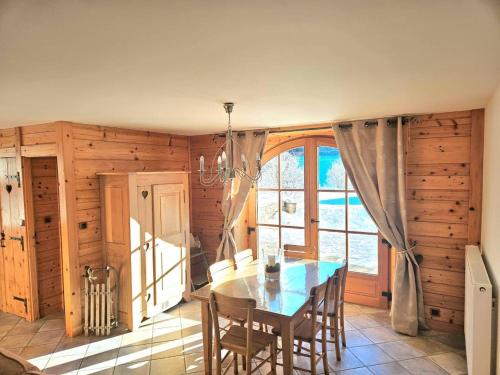 a dining room with a table and a large window at Maison au cœur du Jura in Saint-Laurent-en-Grandvaux