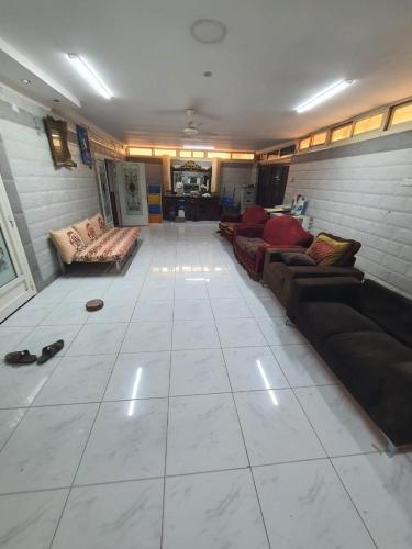 a large living room with couches and a white tile floor at Furnished Bedroom with beside or out side bathroom in Sharjah