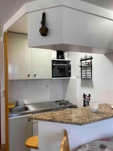 une cuisine avec des armoires blanches et un comptoir dans l'établissement La Plagne - Paradiski - Aime 2000 - Ski aux pieds, à Aime La Plagne