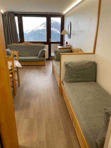 une chambre avec deux lits et un canapé et une fenêtre dans l'établissement La Plagne - Paradiski - Aime 2000 - Ski aux pieds, à Aime La Plagne