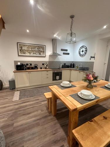 a living room with a wooden table and a kitchen at Abbys Cottage in Windermere