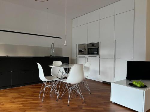 a kitchen with white chairs and a table in a room at Interno 1 - elegante mini affacciato sul verde in Udine