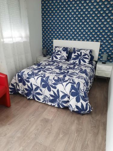 une chambre avec un lit avec une couette bleue et blanche dans l'établissement La conviviale, à Bénouville