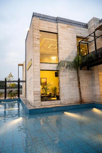 a house with a swimming pool in front of a building at The Farms Club in Islamabad