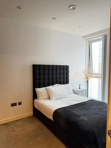 a bedroom with a large bed with a black headboard at Quartz manor in Manchester