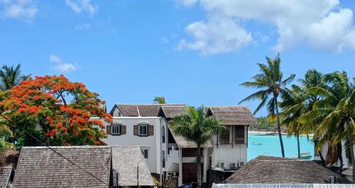 a white house with palm trees and the ocean at Seaview Apartment in Grand Baie