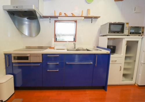 a blue kitchen with a sink and a microwave at 茂平の宿 in Yoro