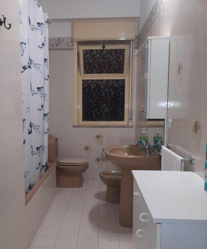 a bathroom with a toilet and a sink and a window at Harmony in Torre Archirafi