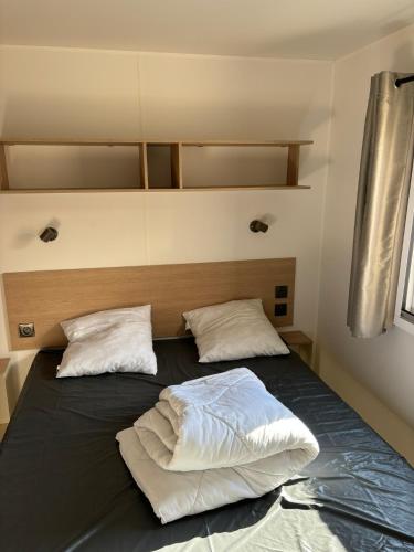 un lit dans une chambre avec deux oreillers dessus dans l'établissement Camping les dunes 5 étoiles - Mobil Home 6 personnes, à Torreilles