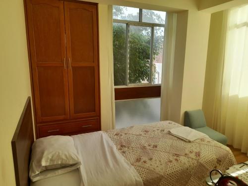 a bedroom with a bed and a dresser and a window at Hermoso apartamento de tres dormitorios con jacuzzi in Chiclayo