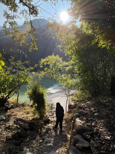 a person walking down a path near a body of water at Samira's Birds & Butterflies Park-Spashram Ganga Beach Retreat in Rishīkesh