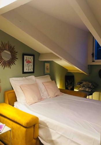 une chambre avec un grand lit blanc et une chaise jaune dans l'établissement Charming flat - Nice port, à Nice