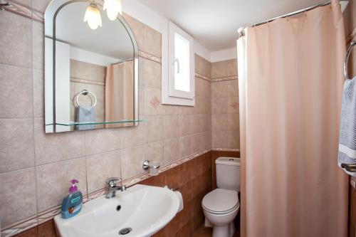 W łazience znajduje się umywalka, toaleta i lustro. w obiekcie Arxontiko w mieście Tinos