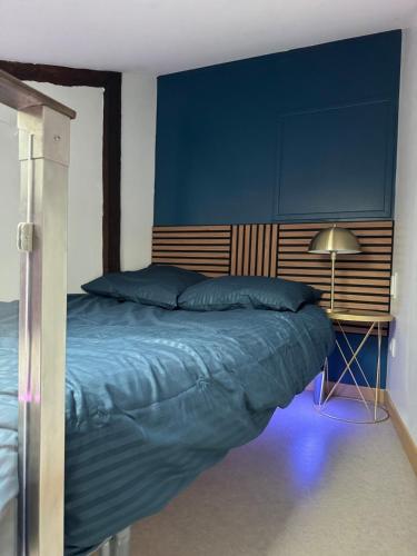 une chambre avec un lit avec un mur bleu dans l'établissement Aux Petits Oignons, à Albi