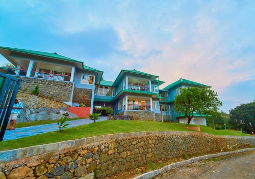 a house on a hill with a stone wall at Priyas Villa Vagamon by VOYE HOMES-Scenic Mountain View in Vagamon