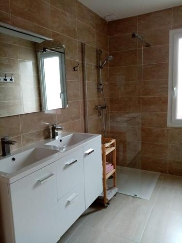 une salle de bain avec un lavabo blanc et une douche dans l'établissement Location maison à 400m de la plage, à Penvins