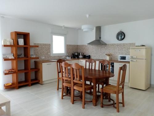 une cuisine avec une table, des chaises et un réfrigérateur dans l'établissement Location maison à 400m de la plage, à Penvins