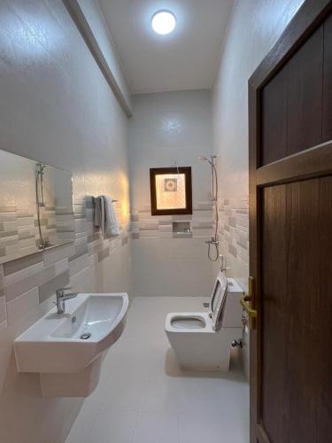 a white bathroom with a sink and a toilet at Modern Desert Gate Resort Bidiyah in Al Raka