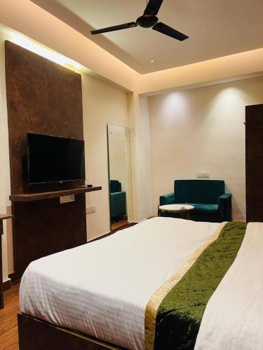 a hotel room with a bed and a flat screen tv at The Taaj Inn in Bengaluru