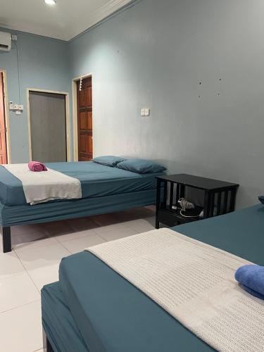 Un dormitorio con dos camas y una mesa dentro. en Hj Hassan Guest House- Studio Unit, en Kuala Terengganu