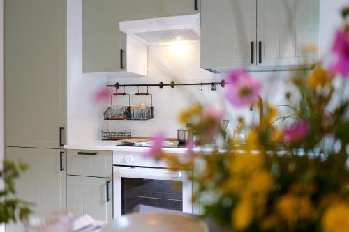 a kitchen with white cabinets and flowers in the foreground at Oltrebosco Casa Vacanze in Valfabbrica