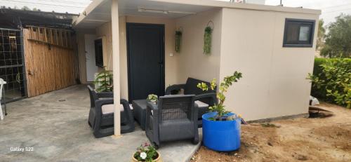 a small house with black chairs and a porch at שקט בערבה in Sappir