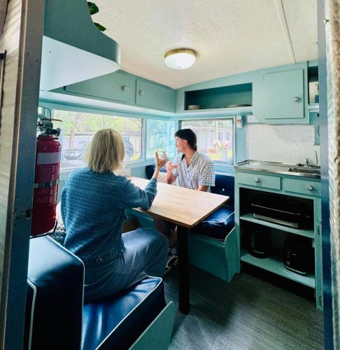 two women sitting at a table in a kitchen at Mornington Peninsula Retro Caravans in Rye
