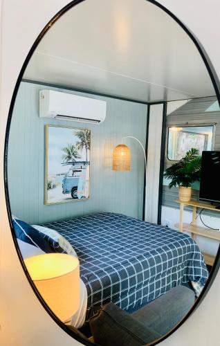 a mirror reflecting a bedroom with a bed in it at Mornington Peninsula Retro Caravans in Rye