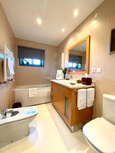 a bathroom with a sink and a toilet and a tub at Condominio encantador, com piscina e vista mar - Ocean View Apartment in Viana do Castelo