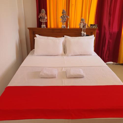 a red and white bed with two white pillows at Guest house weherahena in Matara