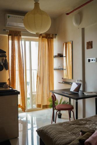 プネにあるRoom Dawn 12th floor Pvt studio w Balcony & Wifiのベッドルーム(ノートパソコン付きのデスク付)
