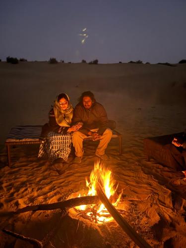 two people sitting around a fire on the beach at Desert Vista Camp Jaisalmer in Jaisalmer