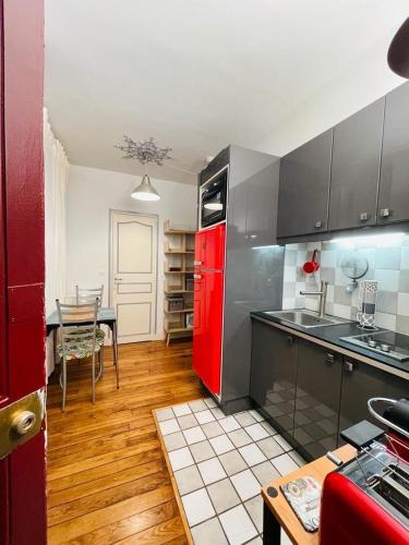 Il comprend une cuisine équipée d'un réfrigérateur rouge et d'une table. dans l'établissement Appartement Tour Eiffel - Invalides, à Paris