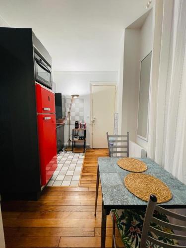 La cuisine est équipée d'une table à manger et d'un réfrigérateur rouge. dans l'établissement Appartement Tour Eiffel - Invalides, à Paris