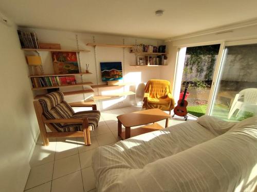 - un salon avec un canapé, des chaises et une guitare dans l'établissement Appartement lumineux au coeur des pins, à Capbreton