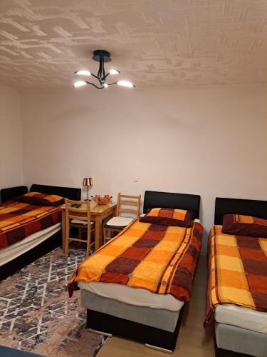 two beds in a room with a table and chairs at Apartmani Konta in Livno