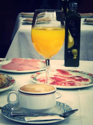 a table with a cup of coffee and a glass of juice at Hostal Pechi in Huévar