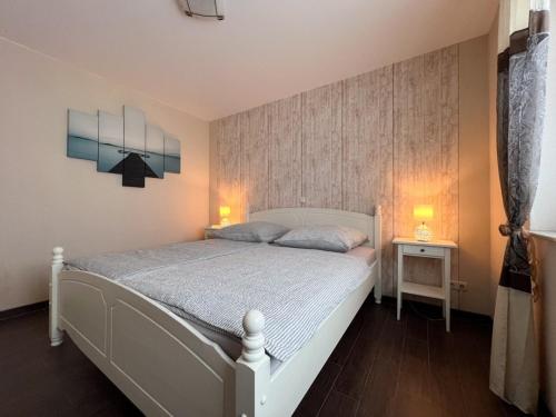 1 dormitorio con 1 cama blanca y 2 lámparas. en Ferienwohnung Kleiner Vilm, en Putbus